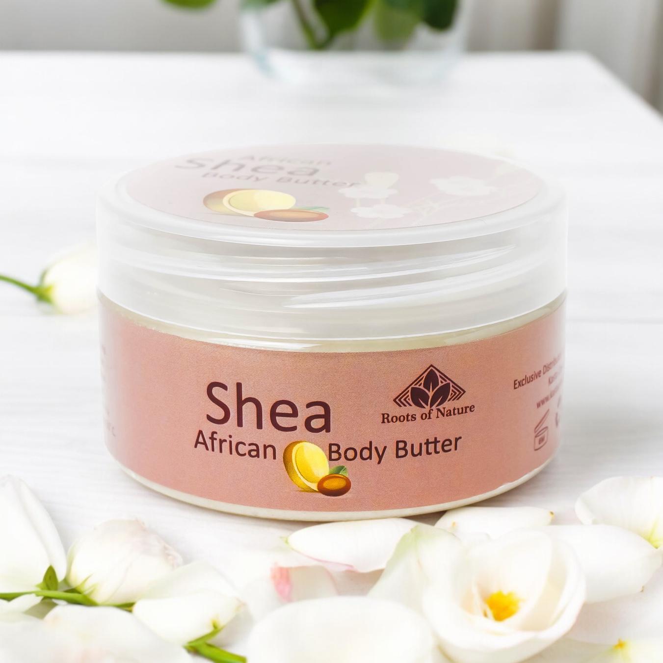 Jar of Shea African Body Butter with a pink label on a white surface with flowers.